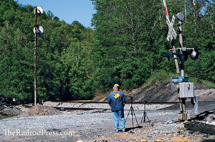 Railfan photographer waiting for the last Ringling Brothers and Barnum & Bailey circus train near the searchlight signal at Itman, West Virginia, with tripods set up at grade crossing